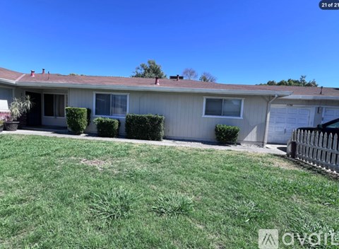 A house with a white fence and green grass in front.