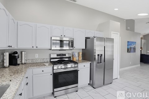 A kitchen with white cabinets and a stainless steel refrigerator.