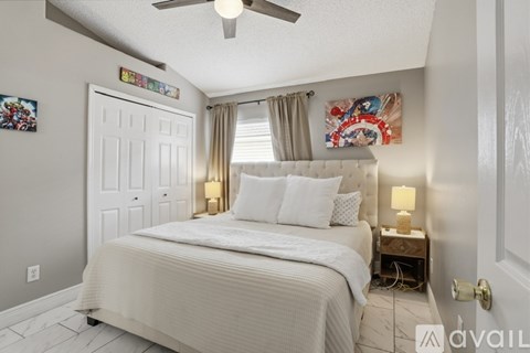 A bedroom with a large bed and a ceiling fan.