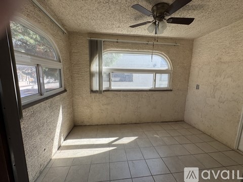 A room with a ceiling fan and a window with a view of the street outside.