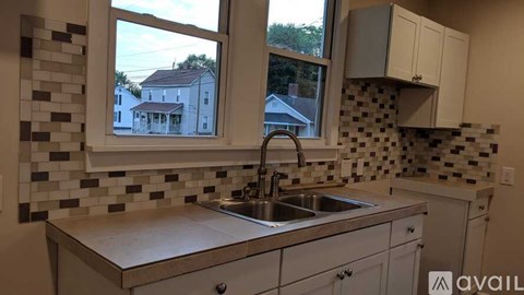 A kitchen with a sink and a window overlooking a house.