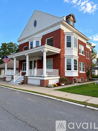 A red brick house with a white porch and a flag on the front.