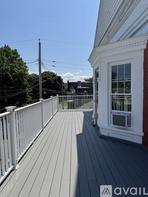 A balcony with a white railing and a white house with a window.