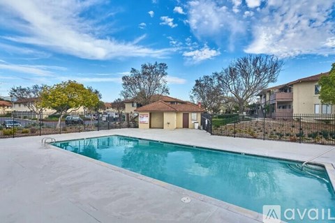 A swimming pool surrounded by a fence with a house in the background.