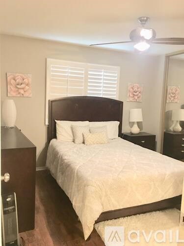 A bedroom with a bed, nightstands, and a ceiling fan.