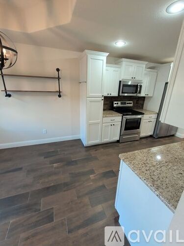A kitchen with white cabinets and a wooden floor.