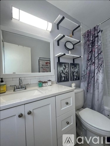 A bathroom with a sink, toilet, and a mirror.