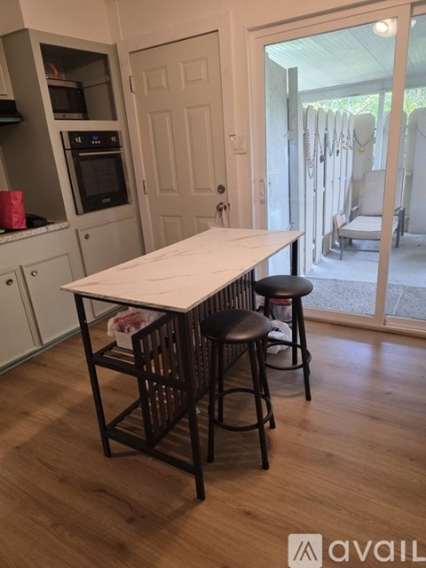 A kitchen with a table and chairs in front of a sliding glass door.