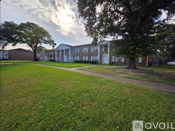 A grassy area in front of a building with a tree on the left.