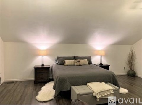A bedroom with a bed, two lamps, and a white furry rug.