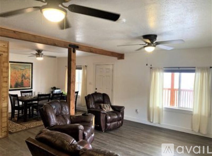 A living room with a brown leather chair and a ceiling fan.