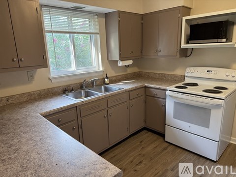 A kitchen with a white stove top oven and a sink with a faucet.