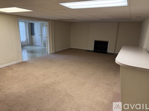 A spacious room with a fireplace and a carpeted floor.