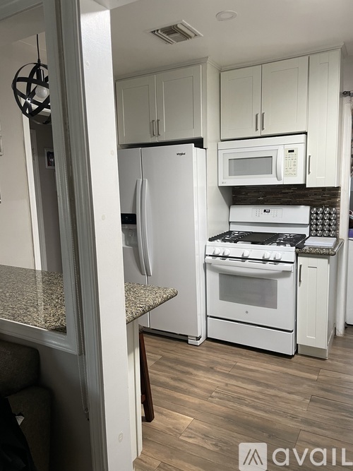 A kitchen with white appliances and cabinets.