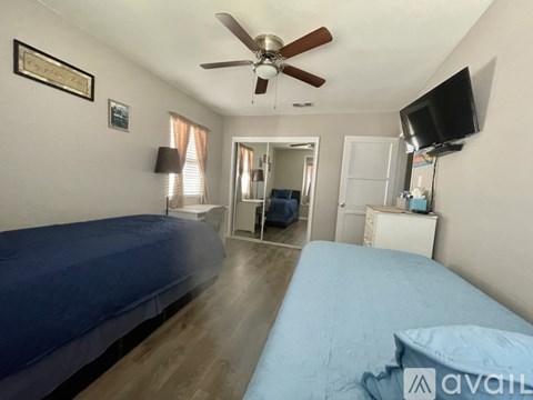 A bedroom with a blue bed and a ceiling fan.