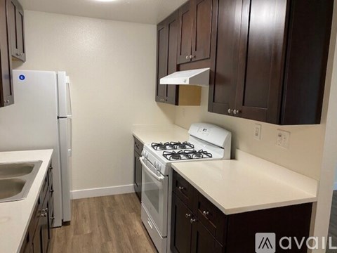 A kitchen with a white fridge, white stove, and brown cabinets.