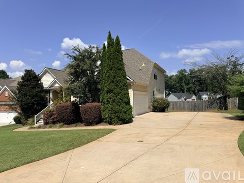 A house with a driveway and a tree in front.