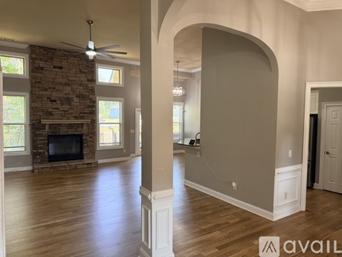 A spacious living room with a stone fireplace and hardwood floors.