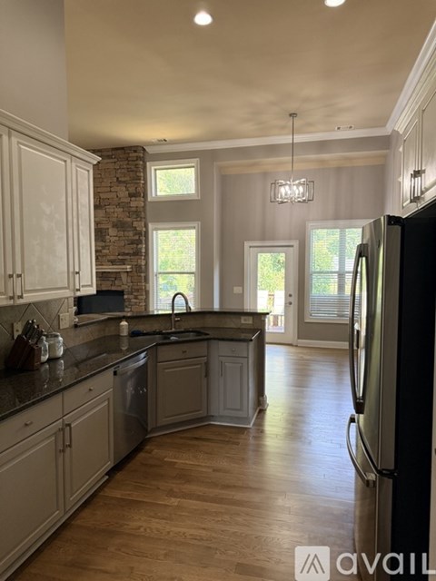 A kitchen with a black fridge and wooden floors.