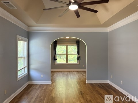 A room with a ceiling fan and a window with a view of trees.