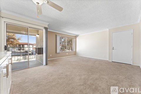 A spacious room with a ceiling fan and sliding glass doors leading to a balcony.