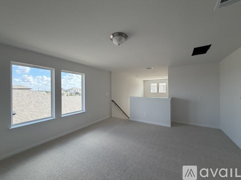 A spacious room with a carpeted floor, a window with a view of the outdoors, and a white ceiling with a light fixture.