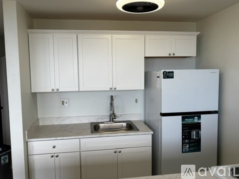 A kitchen with white cabinets and a white fridge.