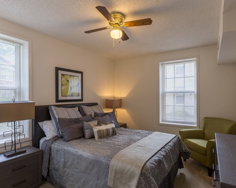 A bedroom with a bed, a chair, and a ceiling fan.