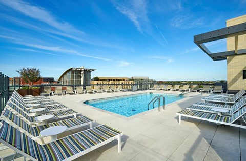 A pool area with sun loungers and a clear blue sky.