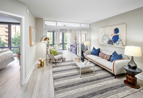 A living room with a white couch and a painting on the wall.