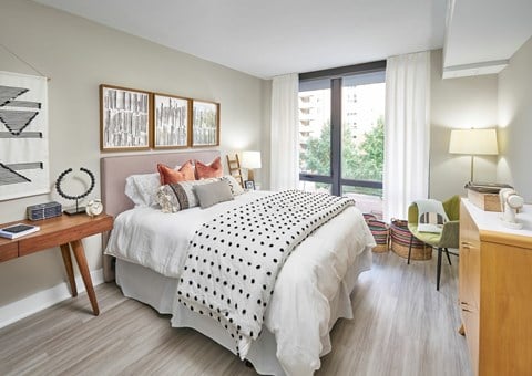 A bedroom with a large bed and a chair by the window.