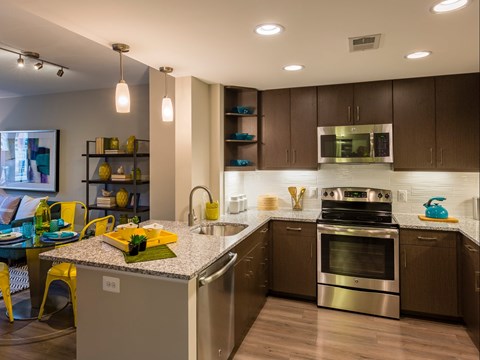 A modern kitchen with dark brown cabinets and stainless steel appliances.