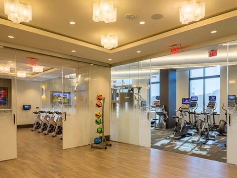 A gym with exercise equipment and mirrors on the wall.