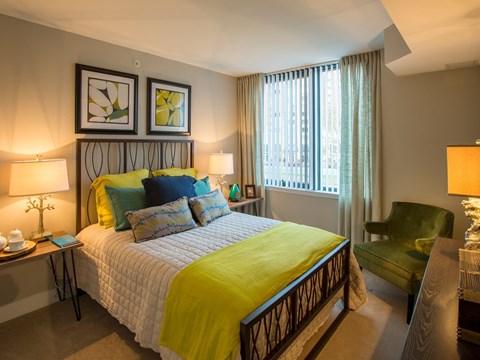 A bedroom with a bed, a chair, and two lamps.