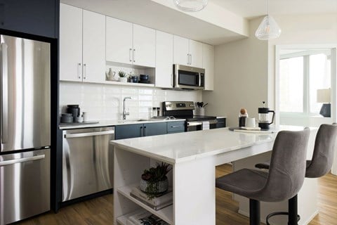 A modern kitchen with a white table and grey chairs.