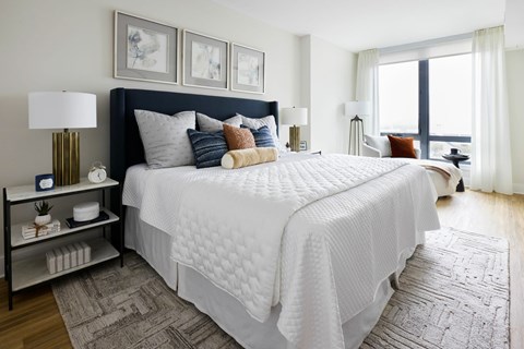 A bedroom with a large bed and a nightstand with a lamp.