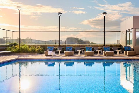 A pool with chairs and a sunset in the background.