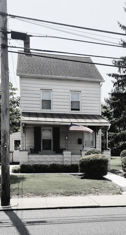 A white house with a grey roof and a small front porch.