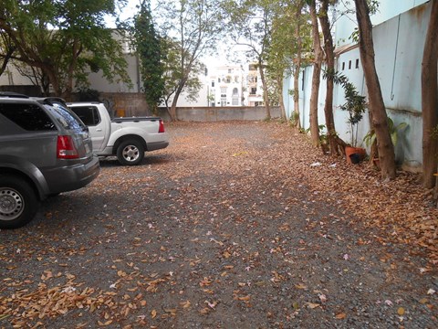 A parking lot with two cars and a wall on the right.