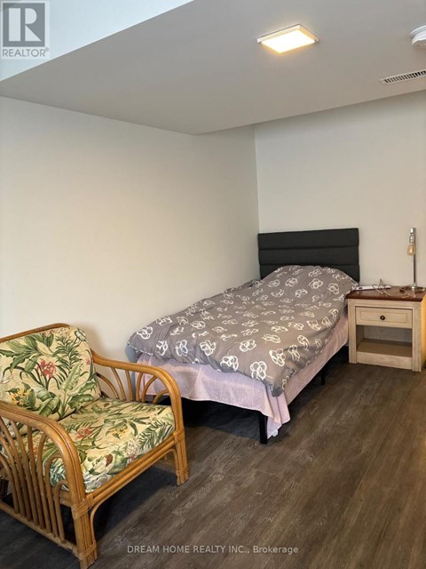 A bedroom with a bed, chair, and nightstand.