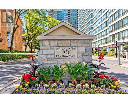 A stone sign with the number 55 and the words Elm Drive West is surrounded by flowers.