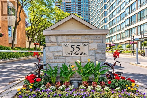 A stone sign with the number 55 and the words Elm Drive West is surrounded by flowers.