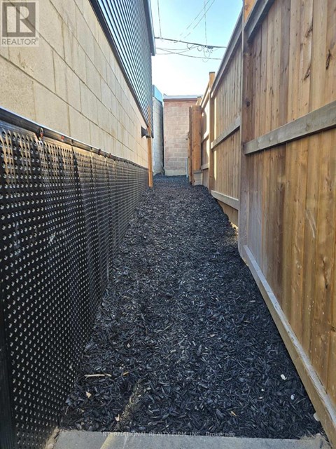 A narrow alley with a wooden fence on one side and a metal fence on the other.