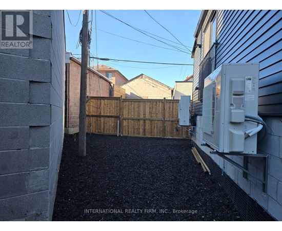 A backyard with a fence and a wall with a Realty sign.