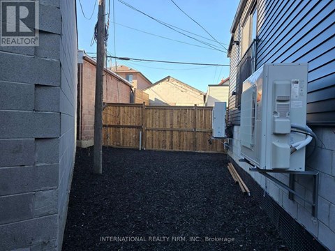 A backyard with a fence and a wall with a Realty sign.
