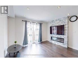 A living room with a stone fireplace and a flat screen TV mounted above it.