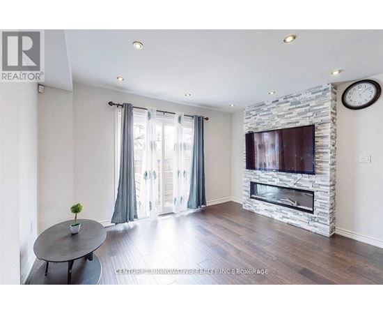 A living room with a stone fireplace and a flat screen TV mounted above it.