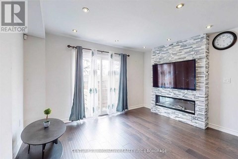 A living room with a stone fireplace and a flat screen TV mounted above it.