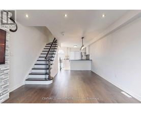 A spacious room with wooden floors and a staircase.