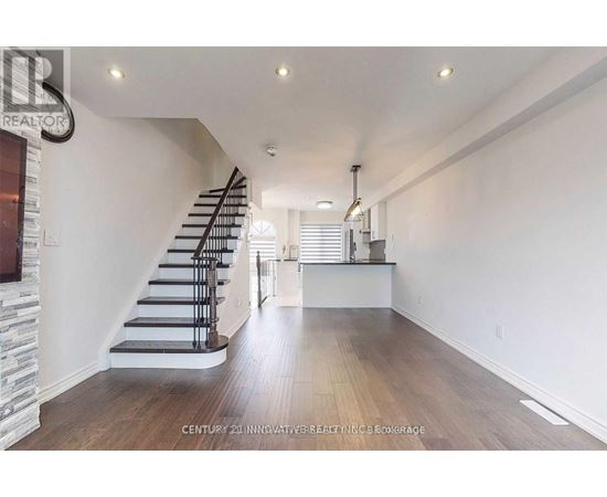 A spacious room with wooden floors and a staircase.